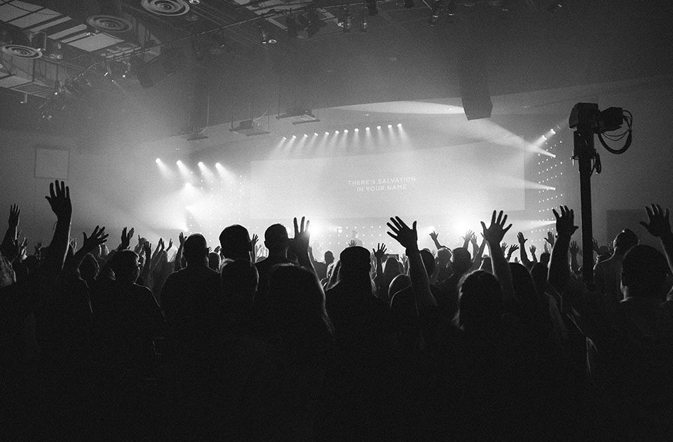 A crowd of people in front of a stage with their hands up.